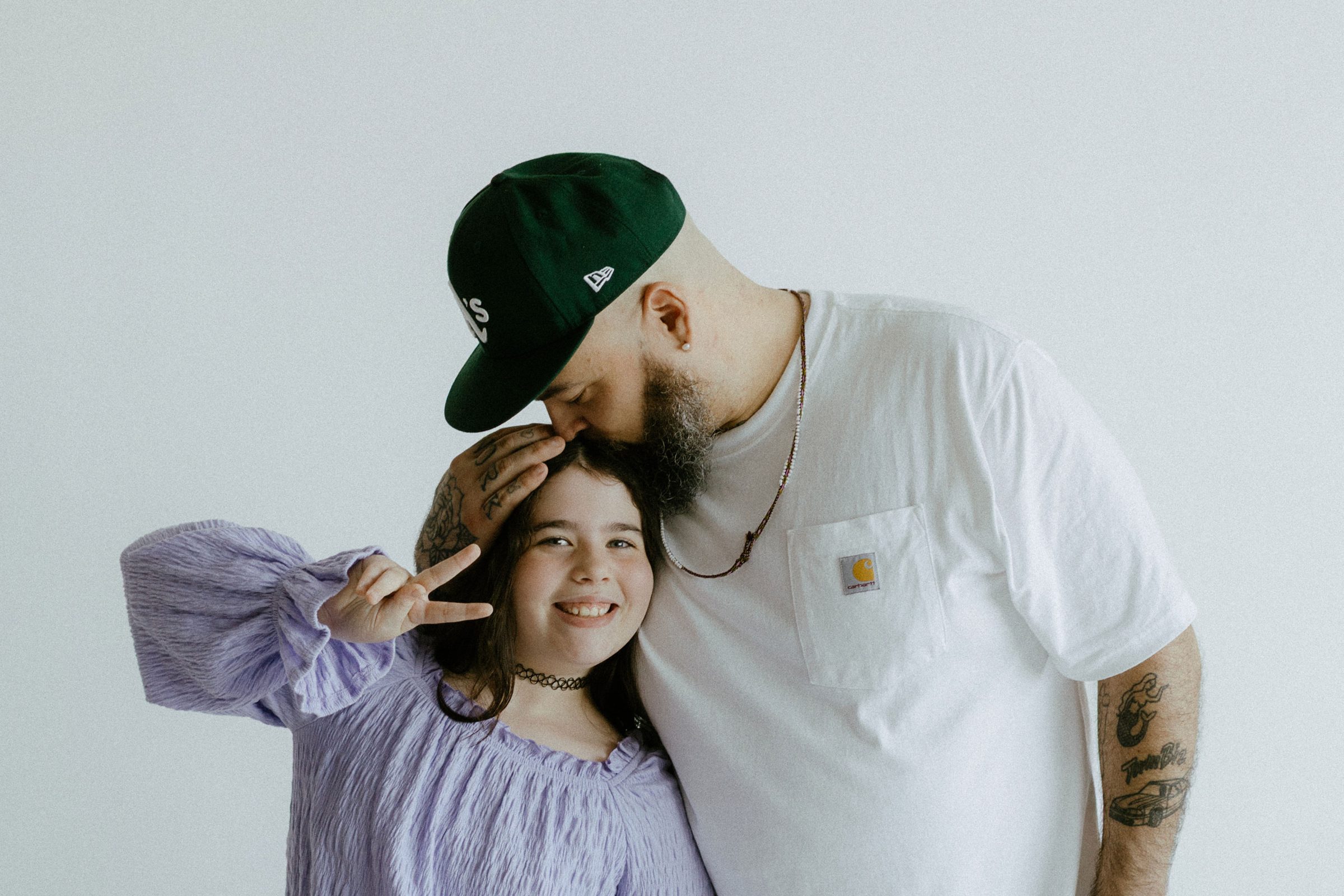 Edrian kissing his daughter's head as she throws a peace sign